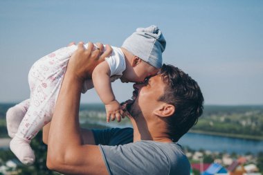 Bebekli bir adam çayırda yürüyor. Köy evleri, orman ve nehir arka planda. Yaz konsepti, sıcaklık, özgürlük, köy hayatı, güneş yanığı