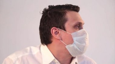 Tıbbi maske takmış beyaz arka planda bir adamın portresi. Tıbbi ekipmanların tanıtımı. Hasta öksürüyor. Karantina, kendini izole etme, koronavirüsten korunma, virüs, hastalık korkusu, tedavi, ilaç, akciğer hasarı