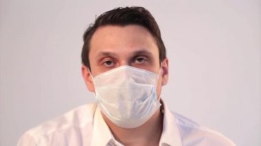 Tıbbi maskeyle nefes alan beyaz arka planda bir adamın portresi. Tıbbi ekipmanların tanıtımı. Karantina, kendini izole etme, koronavirüsten koruma, virüs, hastalık korkusu, tedavi, ilaç