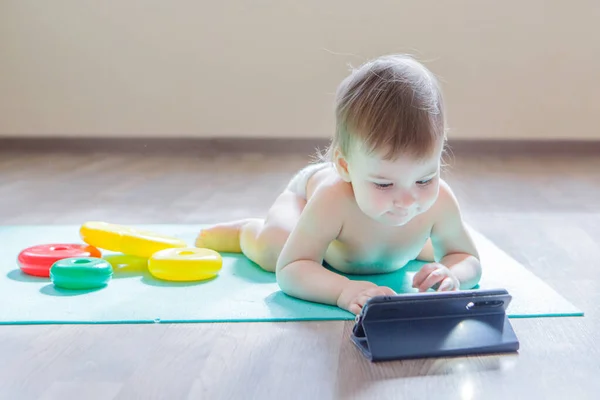 child chose to play with phone instead of toys. girl is watching cartoon, toys are lying around. Concept of advertising of equipment, phones, educational games, childhood, children\'s day, kindergarten