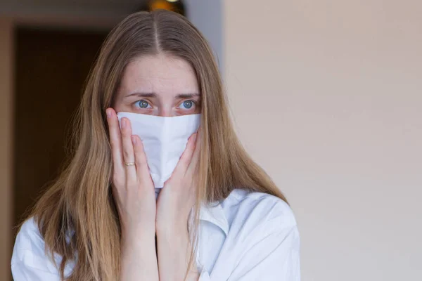 Portrait of a girl who covered her face with a mask. Frightened eyes of the patient. The concept of quarantine, self-isolation, protection from coronavirus, virus, fear of disease, treatment, medicine