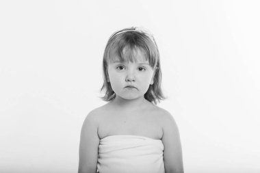 Küçük bir kız, beyaz bir arka plana karşı suratını buruşturuyor. Çocuk bir şeylerin peşinde. Duyguların kavramı, yüz ifadeleri, çocukluk, samimiyet.