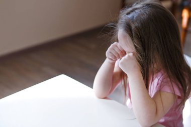 Çocuk sıkıldı, üzgün surat. Kız ağIıyor. Çocukluk konsepti, çocuk günü, anaokulu telif alanı, kötü ruh hali, ev hapsi, itaatsizlik, ebeveynlik, üzüntü, duygular.