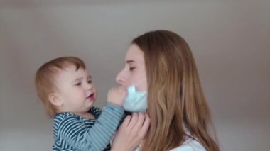 Anne çocukla tıbbi bir maske aracılığıyla konuşuyor. Tıbbi ekipmanların tanıtımı. Karantina, kendini izole etme, koronavirüsten koruma, virüs, hastalık korkusu, tedavi, ilaç