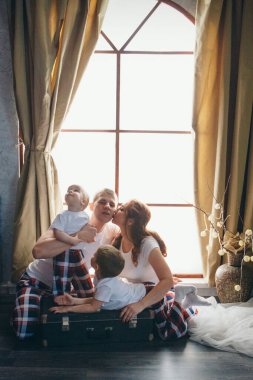 Çocukları olan sevgi dolu bir çift dekoratif bir vazonun yanında yere uzanır. Bir erkek ve bir kadın birbirlerinin gözlerinin içine bakar. Sevgililer Günü. 14 Şubat, Çocuk Günü, Aile Günü