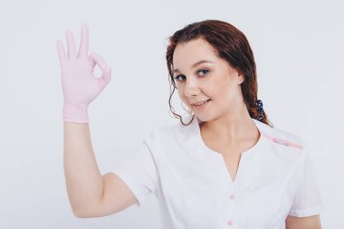 Lastik eldivenli doktor her şeyin yoluna gireceğini gösteriyor. Ücretsiz tıbbi bakım. Hastanedeki gönüllüler için. Kız salgın sırasında bir çeşit koruma takıyor. Beyaz arka planda antiseptik ve tıbbi ekipman ilanları.