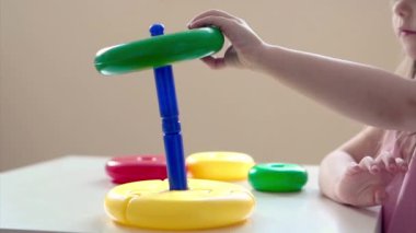 Çocuk bir piramit topluyor. Ellerindeki oyuncağın detayları. İyi motor becerilerin geliştirilmesi, eğitim oyunları, çocukluk, tüp bebek, çocuk günü, anaokulu fotokopi alanı