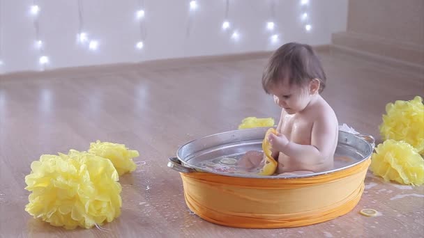 一个小女孩正在用柠檬和柚子洗澡 一个小孩在黄花间的盆子里洗澡 象牙海岸 柑橘疗法的概念 — 图库视频影像