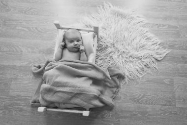 Bebek, bir battaniyenin altında, tahta bir yatakta yatıyor. Küçük bir çocuğun portresi. çocukluk konsepti, sağlık, tüp bebek, çocuk mobilyası, iç mekan, ahşap ürünler