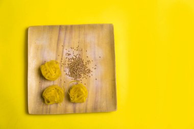 Sarı arka planda diyet ve kilo verme teması. Tahta tabaklarda karabuğday ve makarna ürünleri. Turuncu arkaplanda fotokopi alanı olan yavaş karbonhidratlar. İtalyan ve Rus mutfağı.