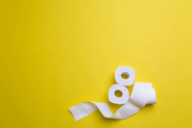 Tuvalet kağıdı sarı arka planda yuvarlanıyor. Kopya uzayındaki günlük nesneler. Coronavirus döneminde hammadde eksikliği. Piyasada popüler bir ürün. Ev için mal teslimatı