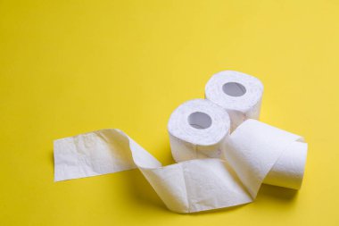Tuvalet kağıdı sarı arka planda yuvarlanıyor. Kopya uzayındaki günlük nesneler. Coronavirus döneminde hammadde eksikliği. Piyasada popüler bir ürün. Ev için mal teslimatı
