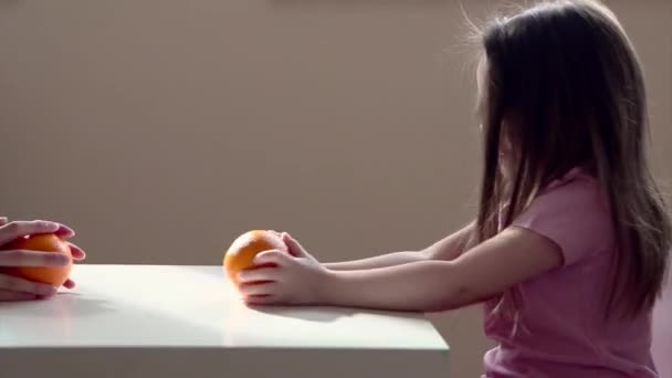 一个小女孩带着橙子扮演一个聪明的母亲 那孩子把水果卷起来 维生素C对你的健康有益 — 图库视频影像