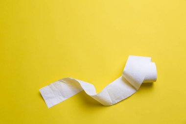 Tuvalet kağıdı sarı arka planda yuvarlanıyor. Kopya uzayındaki günlük nesneler. Coronavirus döneminde hammadde eksikliği. Piyasada popüler bir ürün. Ev için mal teslimatı