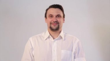Beyaz arka planda tıbbi maske takan bir adamın portresi. Tıbbi ekipmanların tanıtımı. Adam işaret ediyor. Karantina, kendini izole etme, koronavirüsten koruma, virüs, hastalık korkusu, tedavi, ilaç