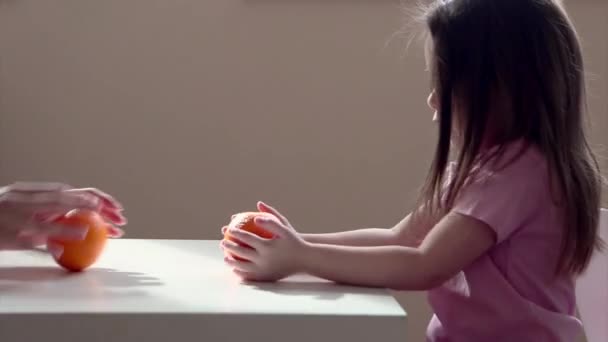 一个小女孩带着橙子扮演一个聪明的母亲 那孩子把水果卷起来 维生素C对你的健康有益 — 图库视频影像