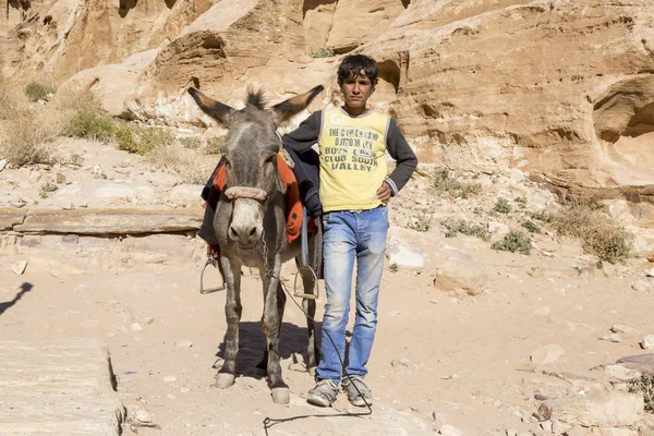 PETRA - JORDANIA - 25 de diciembre de 2015: Niño árabe con su burro en Petra, Jordania — Foto de Stock