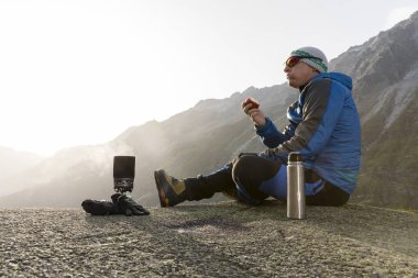 Uzun yürüyüşe çıkan kimse bir mola sırasında bir elma yiyor ve sıcak bir çay hazırlar