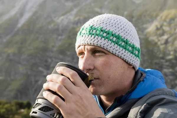 Alpinista posiluje sám s horkým čajem během přísné horské túry — Stock fotografie