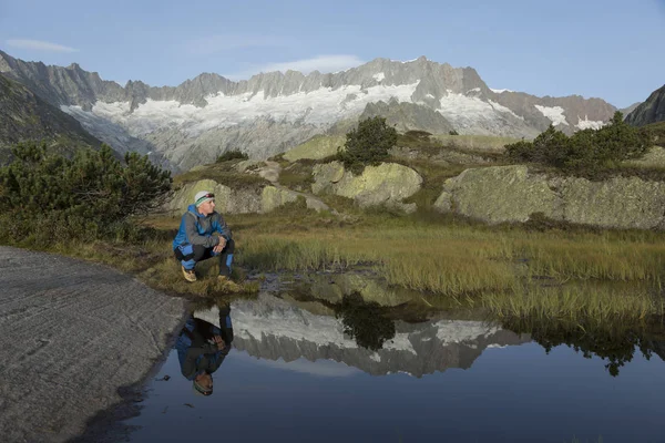 Em um lago montês a paisagem reflete-se. um caminhante faz uma pausa — Fotografia de Stock
