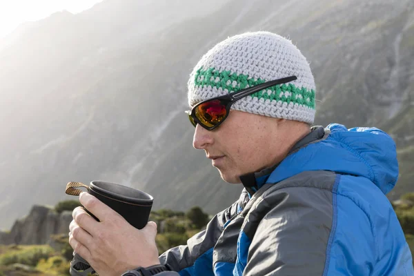 Alpinist fortalece-se com um chá quente durante um rigoroso passeio de montanha — Fotografia de Stock