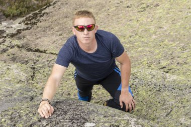 Ciddi görünümlü dagci bir kaya duvarı dibinde duruyor