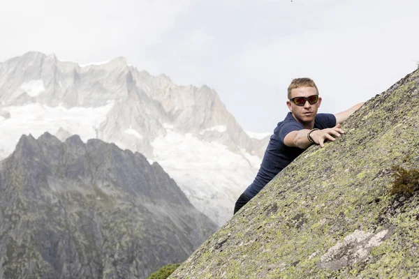 Um alpinista faz exercícios de escalada em uma grande rocha . — Fotografia de Stock