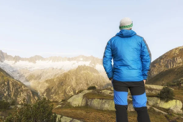 Alpinist stands during the dawn of dawn in front of the mighty mountain scenery in the Swiss Alps — Stock Photo, Image