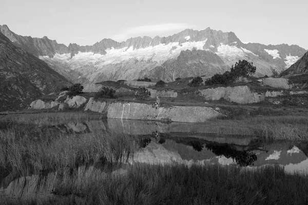 Alpiniste fait une pause lors d'un lever de soleil à un lac de montagne dans les Alpes suisses — Photo