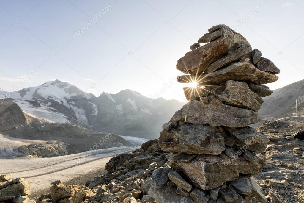 Cairn with sunray in the alps with glacier in the background, Diavolezza, Engandin, Switzerland