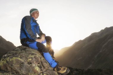 Yakışıklı genç fiyatı bir taşa bir mola ve güneşin doğuşunu swiss dağlarda sahiptir