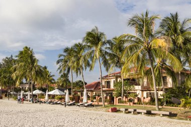 Langkawi, Malezya, 21 Aralık 2017: Beyaz kumlu plaj, Langkawi palmiye ağaçları ve arka planda bungalovlar ile