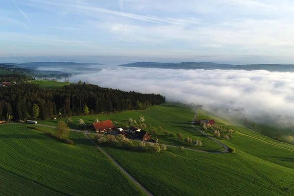 Flygfoto över gårdar i Schweiz på en vårmorgon med vissa morgondimman — Stockfoto