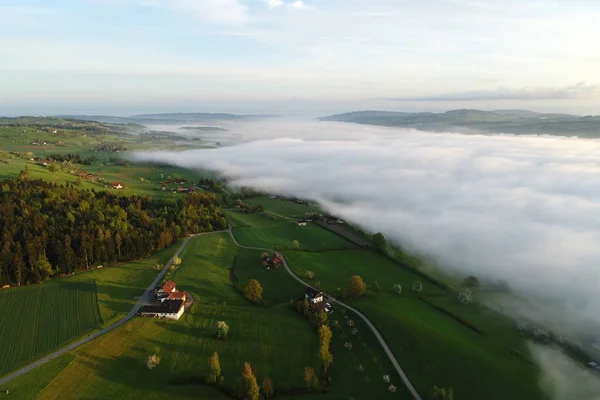 Flygfoto över gårdar i Schweiz på en vårmorgon med vissa morgondimman — Stockfoto