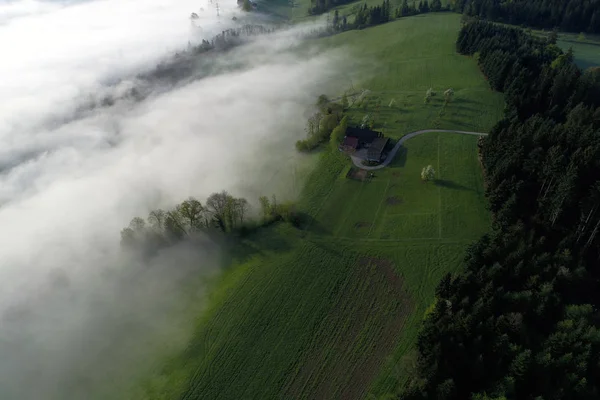 Vista aérea de uma fazenda na Suíça em uma manhã de primavera com algum nevoeiro da manhã — Fotografia de Stock