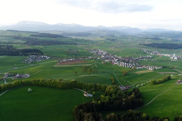 Schweiziska lågland med byar, gårdar och Alperna i bakgrunden på en vårmorgon — Stockfoto