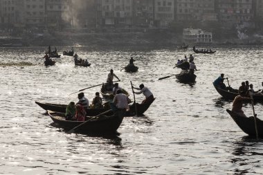 Dhaka, Bangladesh, 24 Şubat 2017: Arkadan aydınlatmalı çekim bir taksi olarak kullanılan küçük ahşap teknelerin Dhaka Bangladeş'te Buriganga Nehri üzerinde işlem yapar