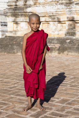Bagan, Myanmar, 29 Aralık 2017: Genç Budist acemi standları bir pagoda Bagan, Myanmar platformu onun kırmızı elbise ile