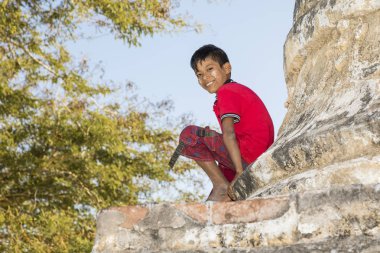 Bagan, Myanmar, 29 Aralık 2017: Yüz Tanaka ile boy gülümseyerek bir stupa Bagan, Myanmar dibinde oturur