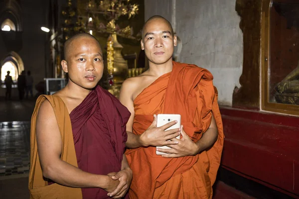 Bagan, Myanmar, 29 de diciembre de 2017: Retrato de dos monjes budistas en la pagoda Ananda en Bagan. Un monje sostiene una tablilla en su mano . —  Fotos de Stock