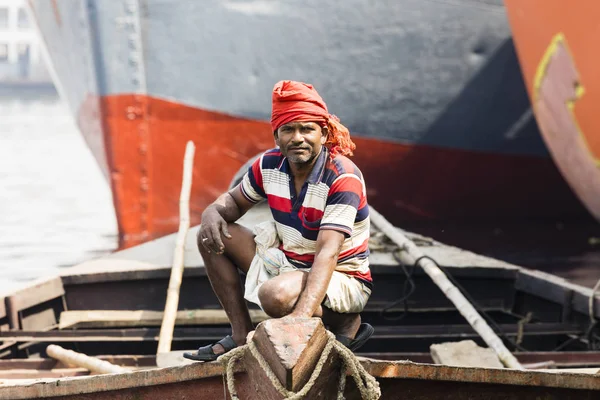 Dhaka, Bangladesz, 24 lutego 2017: Portret wioślarz czeka pasażerów w swojej drewnianej łodzi w Dhaka, Bangladesz. W tle widać łuk statków — Zdjęcie stockowe