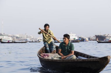 Dakka, Bangladeş, 24 Şubat 2017: Ahşap taksi tekne ile yolcu ve kargo gemisi Dhaka Bangladeş'te Buriganga Nehri üzerinde arka planda