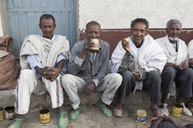 Hamd ela, Etiyopya, Şubat 23 2015: Etiyopyalı erkekler sokakta konuşmak ve eski teneke kutulardan yerel bir içki içme dışarıda oturmak