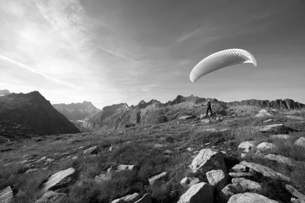 Paraglider Pilot stands on a slope and balances his paraglider above his head in the Alps of Switzerland — Stock Photo, Image