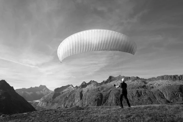 Jonge glijscherm pilot oefeningen met zijn glijscherm omhoog te trekken in de wind, de zogenaamde grondafhandeling. In de omgeving van Grimsel in de Zwitserse Alpen — Stockfoto