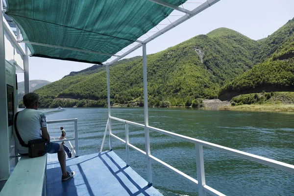 2019年7月7日，阿尔巴尼亚科曼：一名游客坐在栏杆上，欣赏阿尔巴尼亚迪纳利阿尔卑斯山中科马尼湖上的风景 — 图库照片