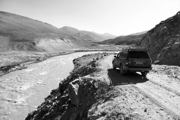 Langar, Tayikistán, 23 de agosto de 2018: El coche todoterreno está esperando en la autopista Pamir, en el río Pamir. A la izquierda del río está Afganistán y a la derecha Tayikistán — Foto de Stock