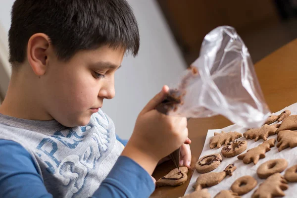 Niño haciendo decoración en galleta de jengibre de cerca. Ingenio para hornear — Foto de Stock