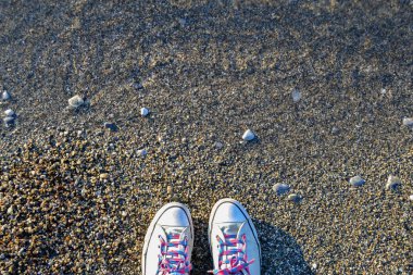 Kavramı ile parlak deniz çakıl taşları üzerinde mavi spor ayakkabı