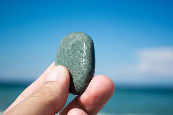 Mão com pedra pequena na praia — Fotografia de Stock